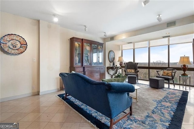 living area featuring light tile patterned floors, baseboards, visible vents, and floor to ceiling windows