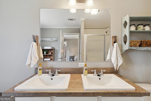 full bath with visible vents, a shower stall, ornamental molding, and a sink