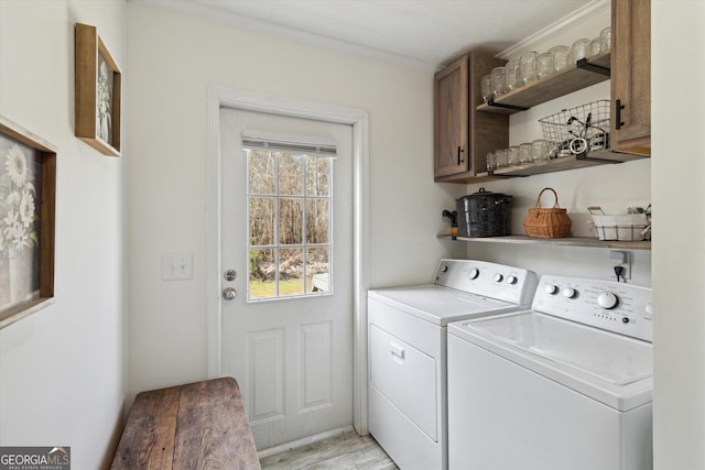 laundry area featuring light wood finished floors, cabinet space, ornamental molding, and washer and clothes dryer