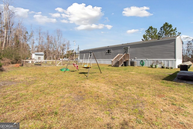 view of yard featuring a playground, fence, and central AC