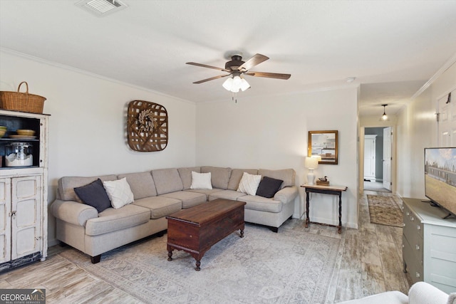 living room featuring ceiling fan, visible vents, wood finished floors, and crown molding