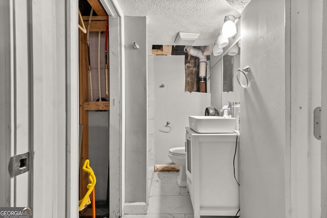 bathroom with marble finish floor, toilet, a textured ceiling, and vanity