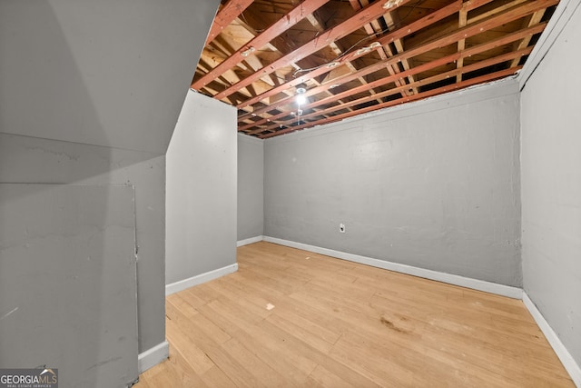 unfinished below grade area with baseboards and wood finished floors