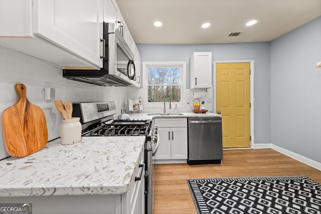 kitchen featuring light wood-style floors, appliances with stainless steel finishes, white cabinets, and a sink