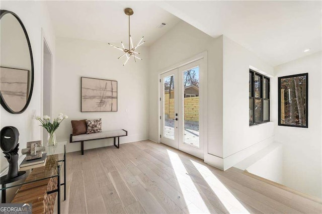 doorway to outside featuring light wood-style floors, french doors, visible vents, and a notable chandelier