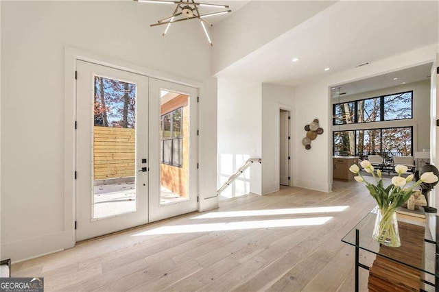 doorway to outside featuring french doors, a high ceiling, and light wood-style floors