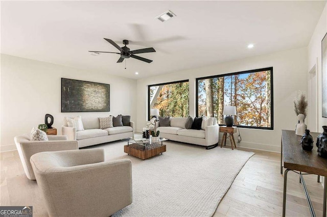 living room with light wood finished floors, a wealth of natural light, visible vents, and baseboards