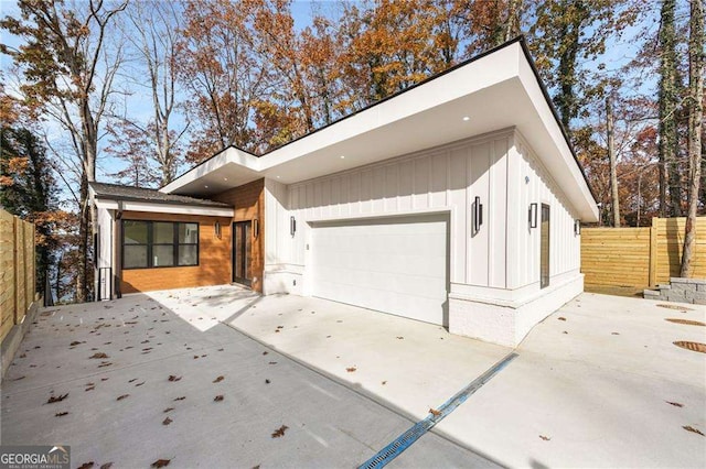 view of front of home featuring a garage, driveway, fence, and board and batten siding