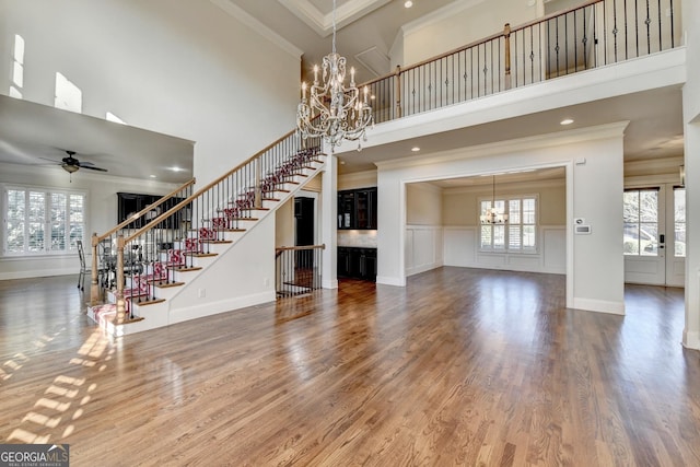 unfurnished living room with ornamental molding, wood finished floors, plenty of natural light, and stairs