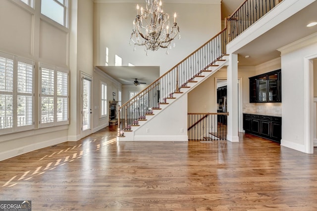 foyer entrance with ornamental molding, stairway, wood finished floors, and baseboards