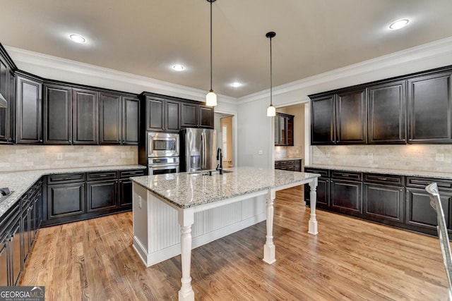 kitchen featuring appliances with stainless steel finishes, a kitchen breakfast bar, decorative light fixtures, crown molding, and light wood-type flooring