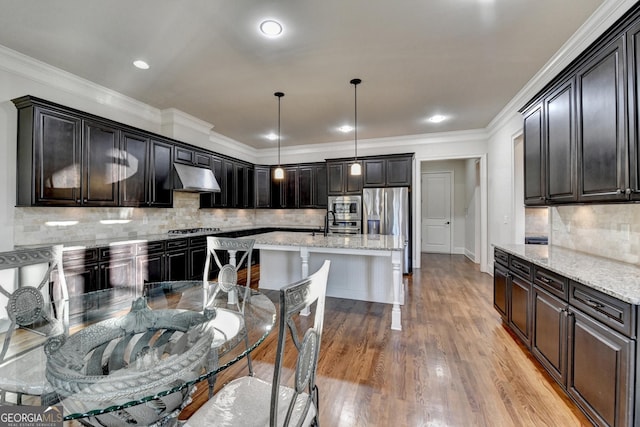 kitchen with light wood-style flooring, light stone counters, ornamental molding, stainless steel appliances, and under cabinet range hood