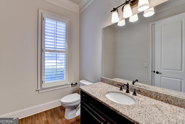 bathroom featuring baseboards, toilet, ornamental molding, wood finished floors, and vanity