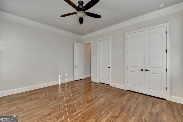 unfurnished bedroom with a ceiling fan, crown molding, baseboards, and wood finished floors