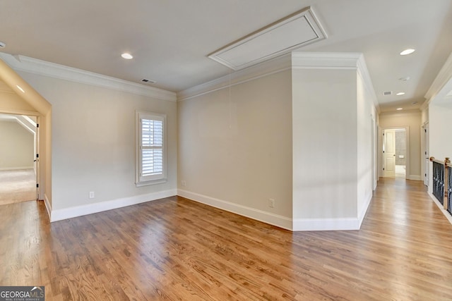 spare room with attic access, visible vents, ornamental molding, and wood finished floors