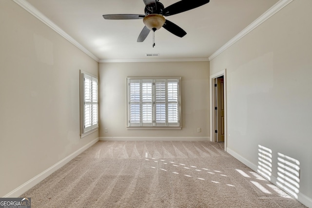 carpeted spare room featuring a ceiling fan, visible vents, baseboards, and crown molding