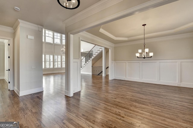 unfurnished dining area with dark wood-style floors, stairs, a decorative wall, and a notable chandelier