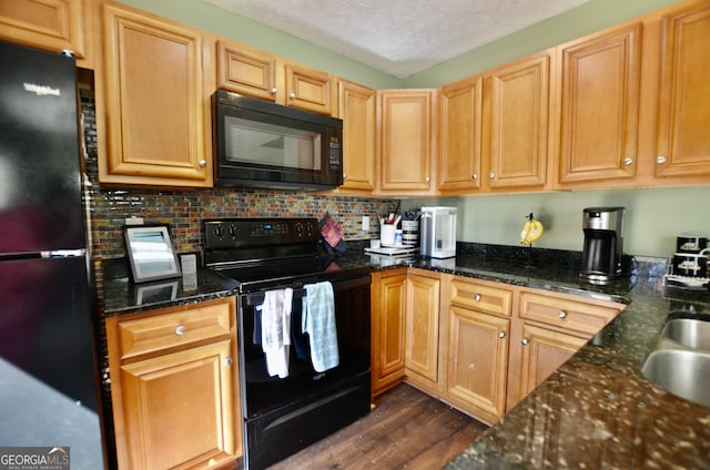 kitchen with dark wood finished floors, backsplash, a textured ceiling, dark stone countertops, and black appliances