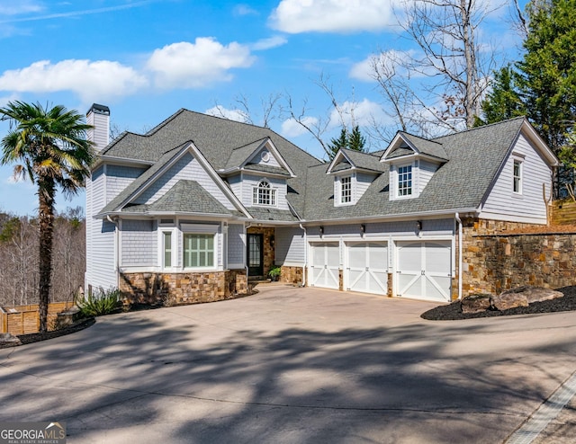 view of front of home featuring stone siding, driveway, an attached garage, and roof with shingles