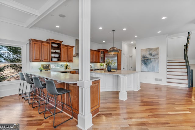 kitchen featuring light countertops, open shelves, a breakfast bar, visible vents, and brown cabinetry