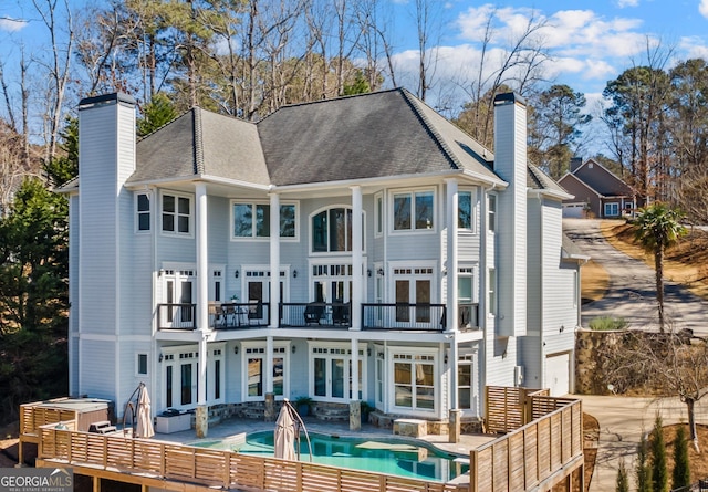 back of house with a balcony, a chimney, a patio area, and french doors