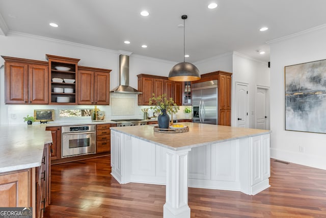 kitchen featuring appliances with stainless steel finishes, brown cabinetry, and wall chimney exhaust hood