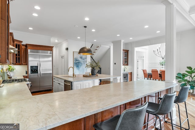 kitchen with ornamental molding, stainless steel appliances, wine cooler, a sink, and ventilation hood