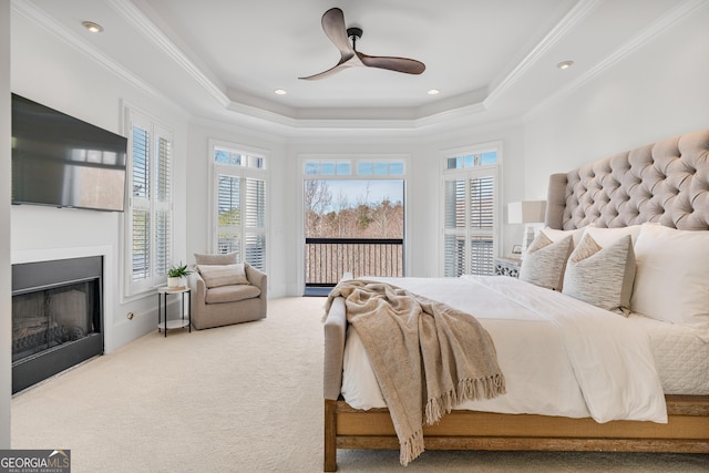 carpeted bedroom with a fireplace, a raised ceiling, ornamental molding, and access to outside