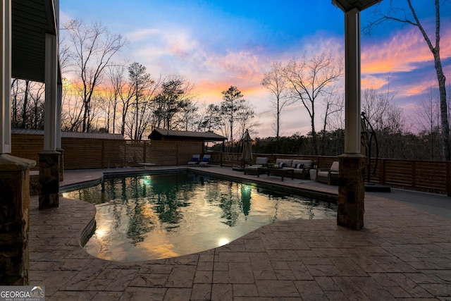 pool at dusk with a patio, a fenced in pool, and fence