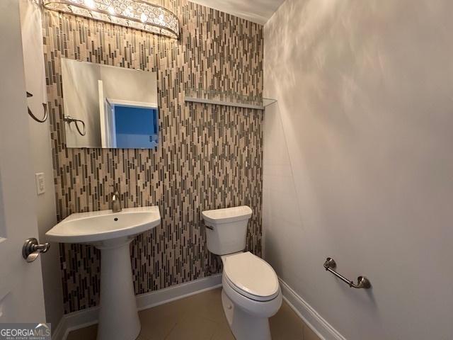 bathroom featuring tile patterned flooring, toilet, and baseboards