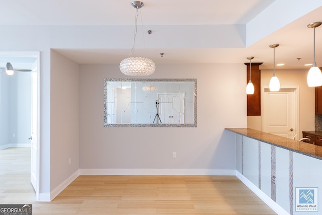 unfurnished dining area with light wood-type flooring and baseboards