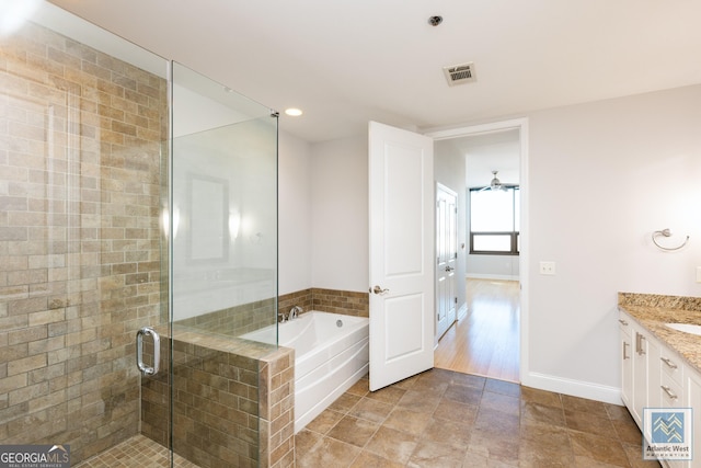 bathroom with a stall shower, visible vents, baseboards, vanity, and a bath