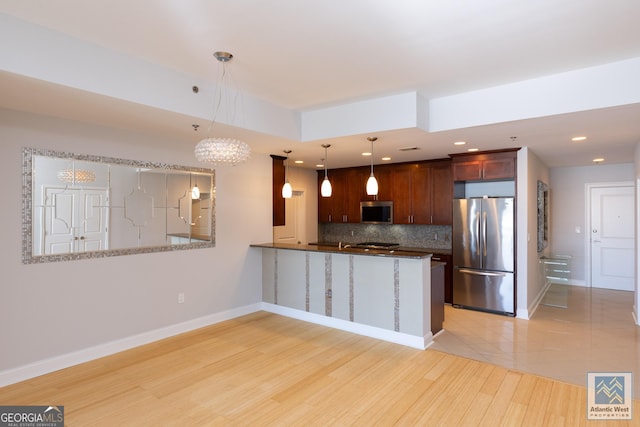 kitchen featuring stainless steel appliances, baseboards, backsplash, and a peninsula