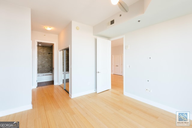 unfurnished bedroom with light wood finished floors, connected bathroom, visible vents, and baseboards