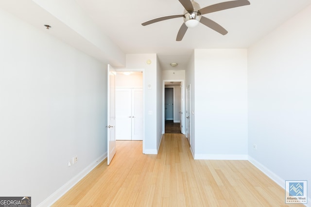 unfurnished bedroom featuring ceiling fan, light wood-type flooring, and baseboards