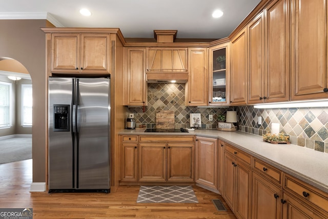 kitchen with crown molding, stainless steel refrigerator with ice dispenser, visible vents, light wood-type flooring, and black electric cooktop