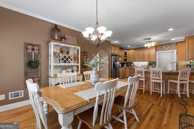 dining space with light wood-style floors, visible vents, and crown molding