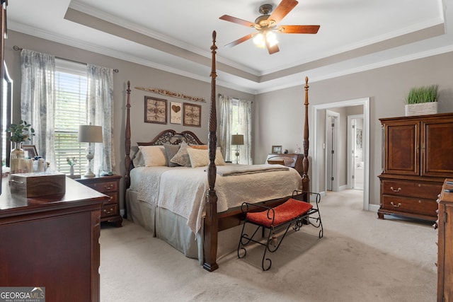 bedroom with light colored carpet, a tray ceiling, multiple windows, and ornamental molding