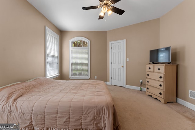 bedroom with a ceiling fan, light colored carpet, visible vents, and baseboards