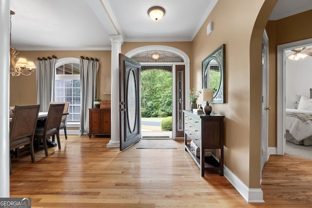 foyer with light wood-style flooring, arched walkways, baseboards, and ornamental molding