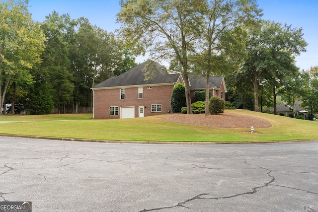 view of home's exterior with brick siding, a yard, driveway, and an attached garage