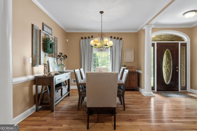 dining area with baseboards, light wood-style floors, crown molding, ornate columns, and a chandelier