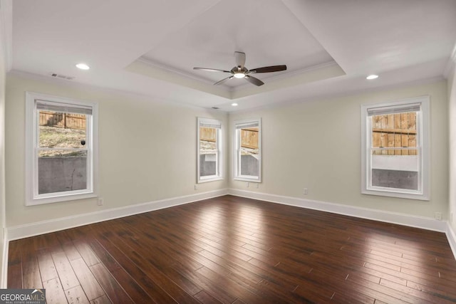 empty room featuring dark wood-type flooring, a tray ceiling, and ornamental molding