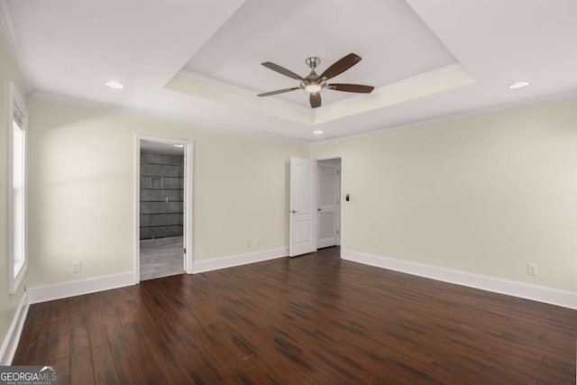 unfurnished bedroom featuring a raised ceiling, ornamental molding, wood finished floors, baseboards, and ceiling fan