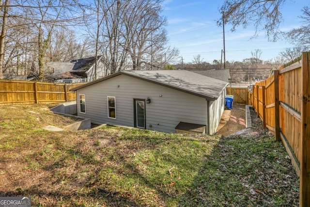 back of house featuring a shingled roof and a fenced backyard