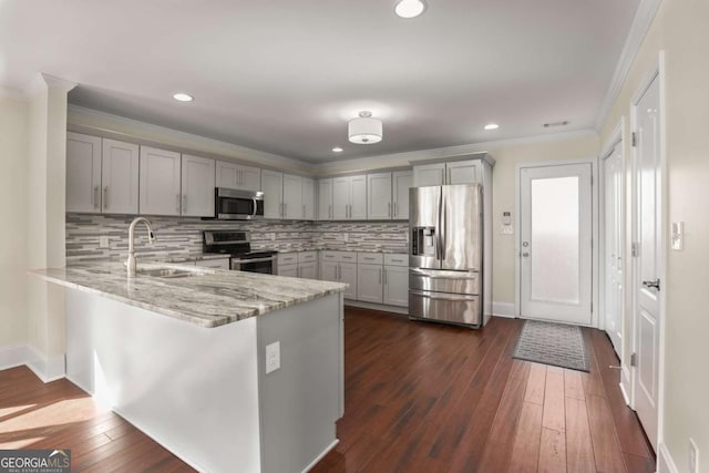 kitchen featuring gray cabinetry, light stone countertops, a peninsula, stainless steel appliances, and a sink