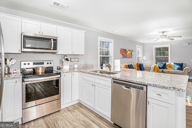 kitchen featuring visible vents, light wood-style flooring, appliances with stainless steel finishes, a sink, and a peninsula