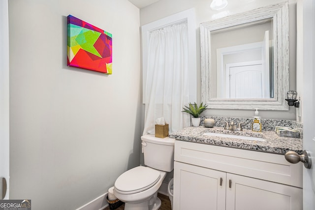 bathroom with toilet, baseboards, and vanity