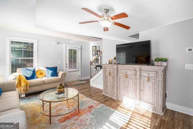 living area with stairway, wood finished floors, and baseboards