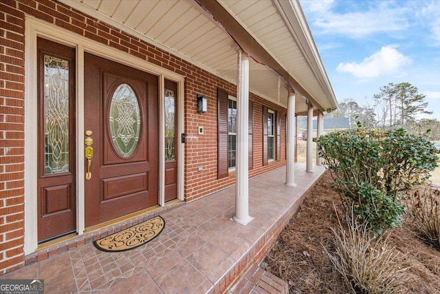 entrance to property featuring covered porch and brick siding